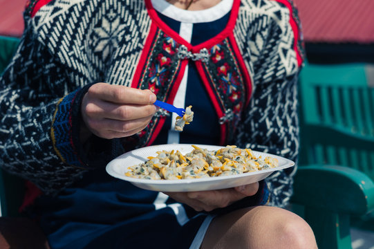 Young woman eating cockles outside
