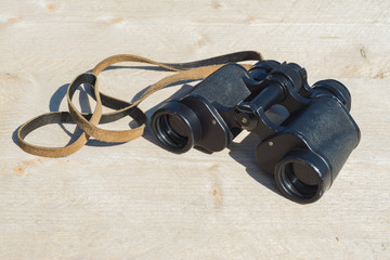Old binoculars lying on a wooden board
