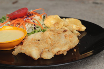 fish steaks and vegetable salad with french fries.