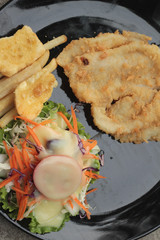 fish steaks and vegetable salad with french fries.