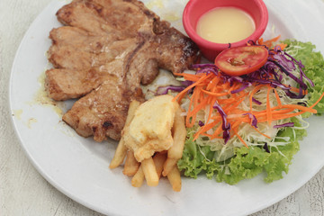 steaks and vegetable salad with french fries.