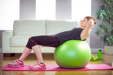 Fit woman doing sit ups on exercise ball