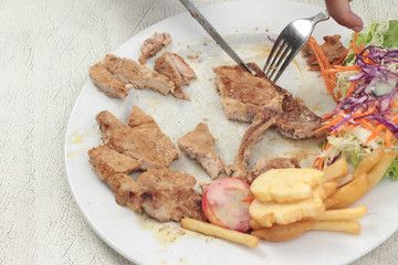 steaks and vegetable salad with french fries.