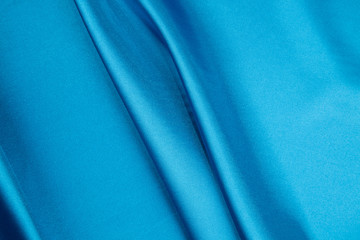 Soft folds of deep blue silk cloth texture.