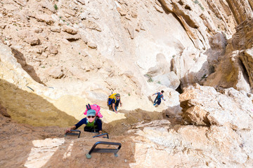 Group of three backpackers hiking desert canyon.