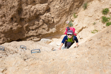 Obraz premium Young woman climbing desert canyon cliff.