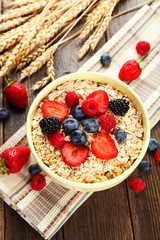 Oatmeal with berries on brown wooden background