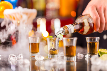 Barman pouring hard spirit into glasses