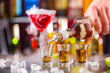 Barman pouring hard spirit into glasses