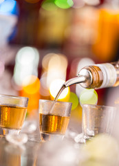 Barman pouring hard spirit into glasses