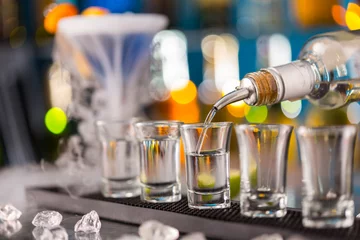 Glasschilderij Alcohol Barman schenkt sterke drank in glazen