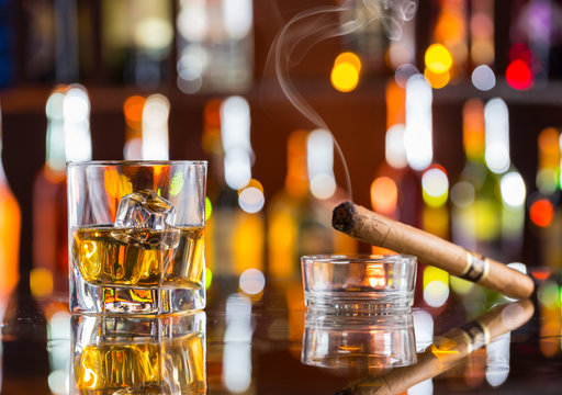Whiskey drink with smoking cigar on bar