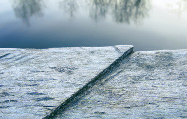 Trees reflections on the surface of lake and wooden background