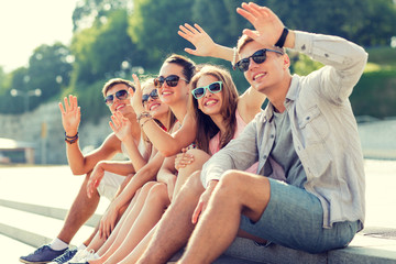 group of smiling friends sitting on city street © Syda Productions
