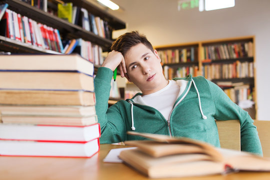 bored student or young man with books in library