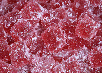 Background of tasty red jelly cubes covered in sugar