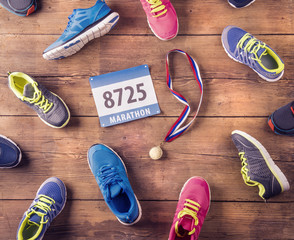 Running shoes, number and gold medal on a wooden background
