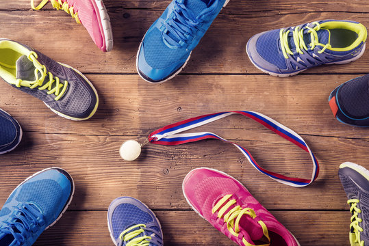 Running Shoes And Gold Medal On A Wooden Floor Background