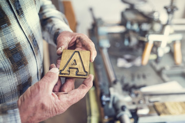 Senior man holding a letter that is used for engraving