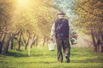 Farmer with jug and bucket for milking outside in green nature