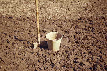 Ведро и лопата на фоне вскопанной гряды