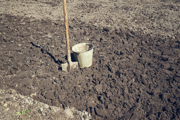 Ведро и лопата на фоне вскопанной гряды