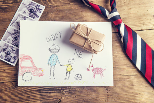 Tie, childs drawing, present and pictures on wooden background