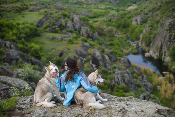 girl sitting with sled dogs looking at view outdoors