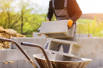 Unrecognizable bricklayer building a wall loading a wheelbarrow 