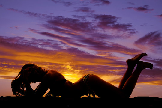 silhouette of a woman in a bikini lay on stomach butt up