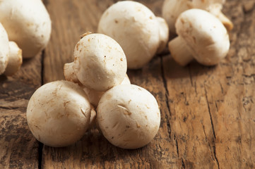 White mushrooms in a bowl on wooden table, selective focus