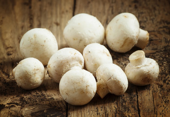 White mushrooms in a bowl on wooden table, selective focus
