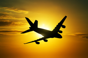 Airplane flying above  sunset sky