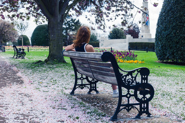 Elegant woman on park bench with cherry blossom