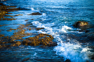 Sea waves with foam on the stony shore. Toned