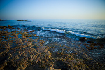 Sea waves with foam on the stony shore. Toned