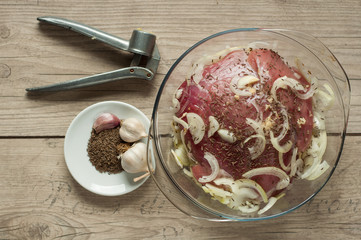 pork meat in roaster with onion cumin and garlic on wooden table