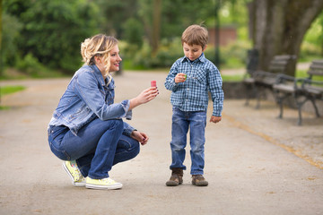 Cute little boy playing with his mother outdoors 