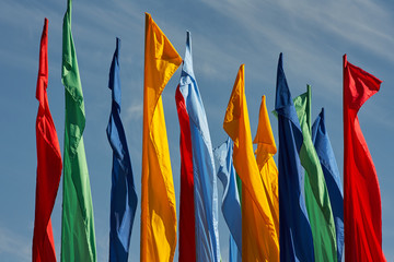 multicolored flags against the blue cloudy sky