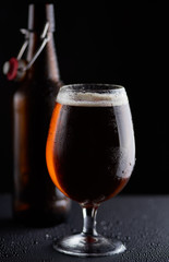 beer bottle and a cup on a black background