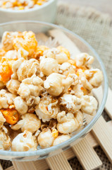A bowl of popcorn on a wooden table, caramel popcorn
