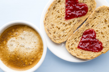 Fresh coffee. Grain slice of bread with jam heart shape.