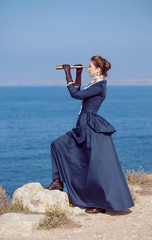  Romantic young beautiful lady looks at spyglass outdoors