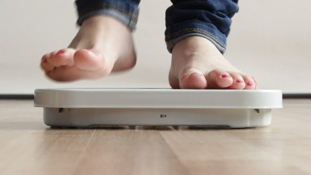 Woman stepping on scales. Full HD 1920X1080P