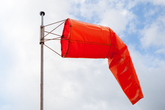 Windsock. Red wind indicator over cloudy sky