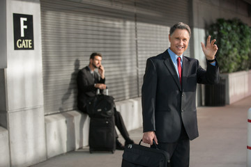 Man in suit traveling signals for a lift from a taxi