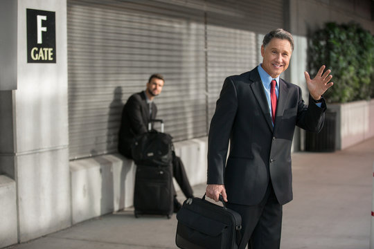 Executive man greets a ride share vehicle in a suit at airport
