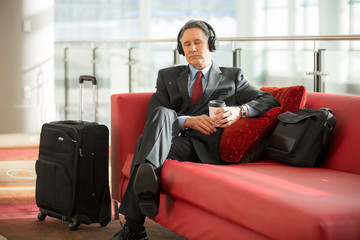 Business man meditates while at the airport listening to music