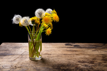 Dandelions in glass on wood table
