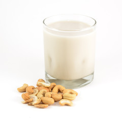 A glass of cashew milk with a pile of cashews